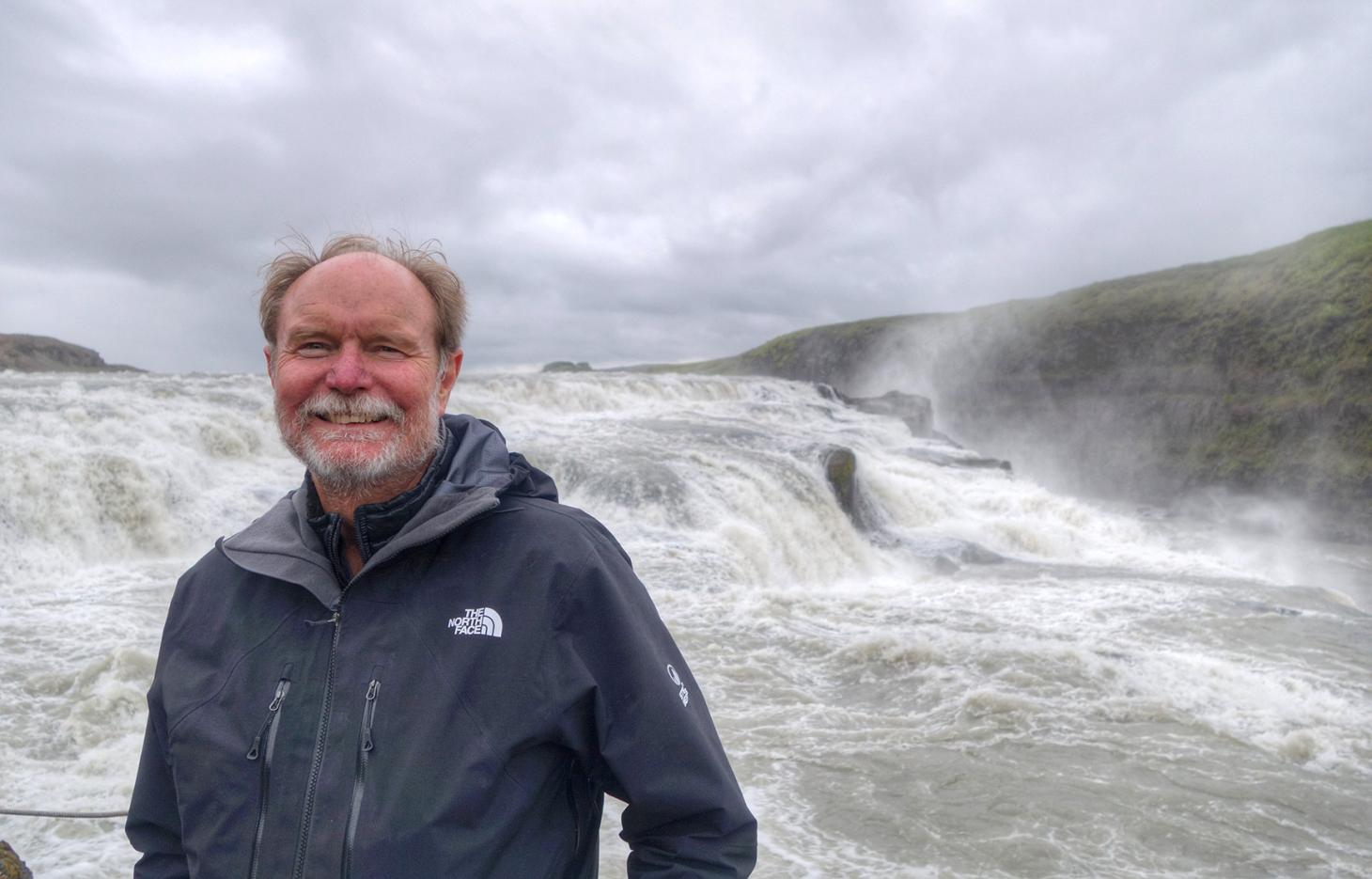 Joel Peterson standing in front of white water rapids.