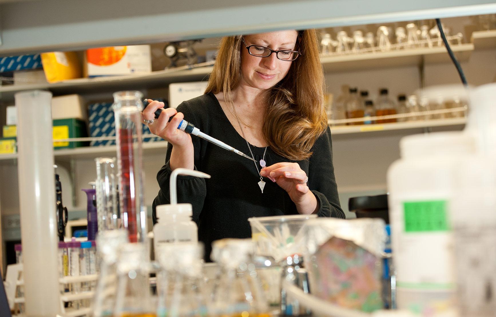 A biologist working with a vial in a lab.